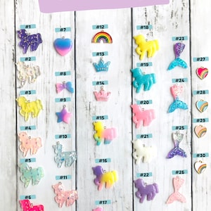 May include: Thirty resin charms in various colors and designs, including unicorns, rainbows, hearts, stars, and mermaid tails. Each charm is numbered from 1 to 30.