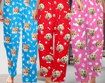 May include: Three pairs of pajama pants in blue, red, and pink. The blue pants feature cat faces, fish bones, and paw prints. The red pants have dog faces, bones, and paw prints. The pink pants have cat and dog faces, fish bones, and paw prints.
