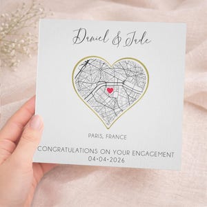 May include: A white engagement card with a gold heart-shaped map of Paris, France, and a red heart marking a location. The card is inscribed with "Daniel & Jade", "Paris, France", and "Congratulations on your engagement 04.04.2026".