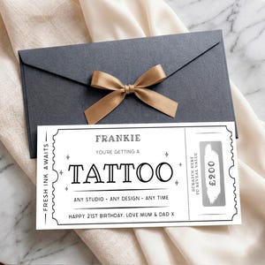 May include: A dark grey envelope with a gold ribbon bow and a white rectangular gift voucher. The voucher features black text reading Frankie, You're Getting A Tattoo, Fresh Ink Awaits, and Happy 21st Birthday, Love Mum & Dad X, with a scratch-off panel.