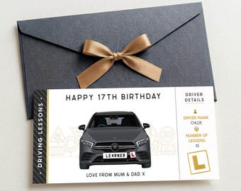 May include: A rectangular gift voucher for driving lessons featuring a dark grey car illustration, the text HAPPY 17TH BIRTHDAY, and a driver details section for Chloe with 10 lessons. The voucher is placed below a dark grey envelope with a gold ribbon.