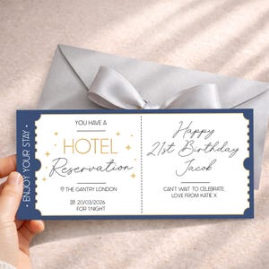 May include: A navy blue and white hotel reservation ticket with gold accents. The ticket reads "Happy 21st Birthday Jacob" and "Hotel Reservation" with the location and date. A gray envelope with a white ribbon is in the background.