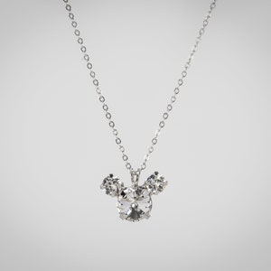 Puede incluir: Un collar de cadena de plata con un colgante de Mickey Mouse de cristal.