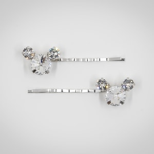 May include: Two silver hair clips with clear rhinestone accents in the shape of Mickey Mouse ears.