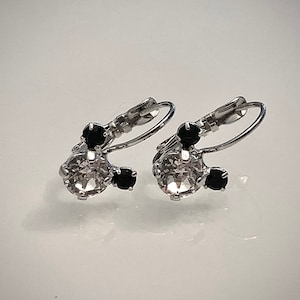 Puede incluir: Un par de pendientes de plata con un gran cristal de roca transparente y tres cristales de roca negros más pequeños.