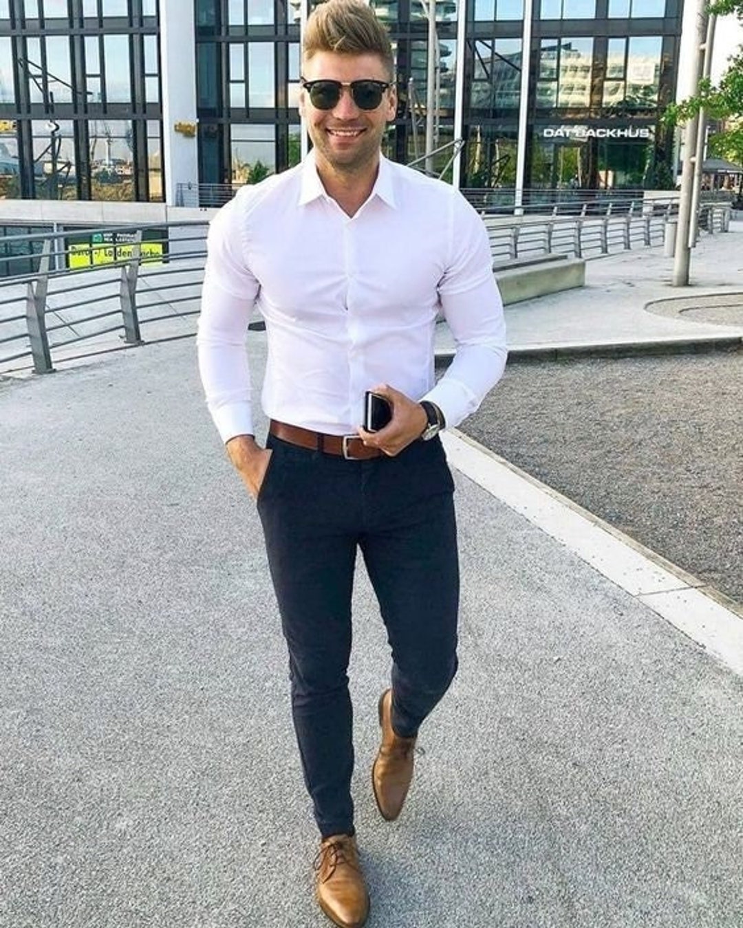 Portrait of Young African American Man in New York City Wearing blue  blazer white shirt blue pants white sneakers young black college  student standing against silver metal wall on campus think Stock