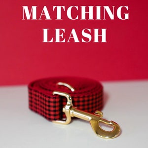 May include: Red and black plaid dog leash with a gold metal clasp. The leash is coiled up and the text "MATCHING LEASH" is visible above the leash.