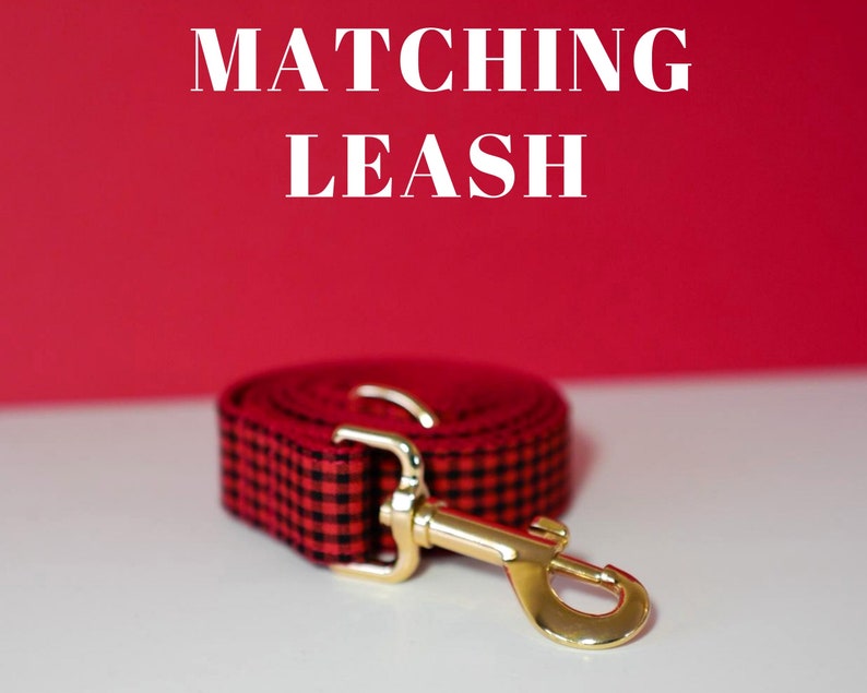 May include: Red and black plaid dog leash with a gold metal clasp. The leash is coiled up and the text "MATCHING LEASH" is visible above the leash.