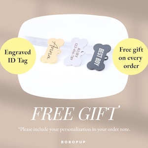 May include: Three dog bone-shaped engraved ID tags. The tags are gold, silver, and black. The gold tag says "Anna", the silver tag says "RUBY 123-456-789", and the black tag says "BEST BOY". The text "Engraved ID Tag" is in a yellow circle on the left side of the image. The text "Free gift on every order" is in a yellow circle on the right side of the image. The text "FREE GIFT" is in large letters below the tags. The text "*Please include your personalization in your order note." is below the large text. The text "BOBOPUP" is at the bottom of the image.