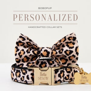 May include: Personalized dog collar and bow tie set in a leopard print pattern with gold hardware. The collar has a black strap with a gold buckle and a gold tag that says "Nellie 541554/181". The bow tie is made of the same leopard print fabric and has a gold loop for attaching to the collar.
