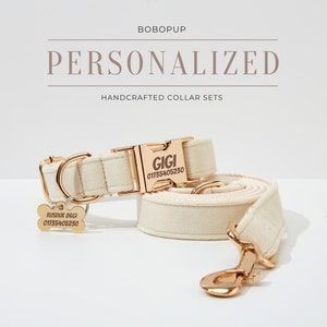 May include: A white canvas dog collar and lead set with gold hardware. The collar has a gold buckle with the name "GIGI" and phone number "01755405230" engraved on it. The lead has a gold hook.