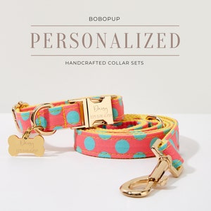 May include: A pink and yellow dog collar set with blue polka dots. The collar and leash are both personalized with the name "Daisy" and a phone number. The set features gold hardware.