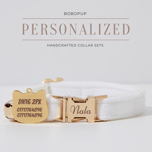 Könnte beinhalten: Weißes Katzenhalsband mit einer goldenen Schnalle, die mit dem Namen "Nala" graviert ist. Das Halsband hat außerdem ein goldenes, katzenförmiges Schild mit dem Text "DN16 2PX" und Telefonnummern.