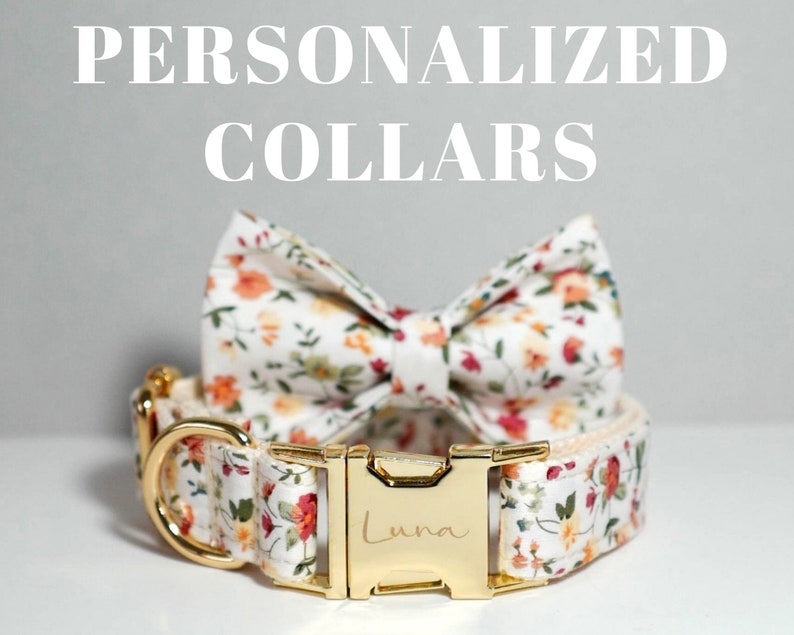 May include: A white dog collar with a floral pattern and a gold buckle. The buckle is engraved with the name "Luna". The collar is paired with a matching floral bow tie.