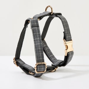 May include: A gray and white plaid dog harness with gold-toned hardware.