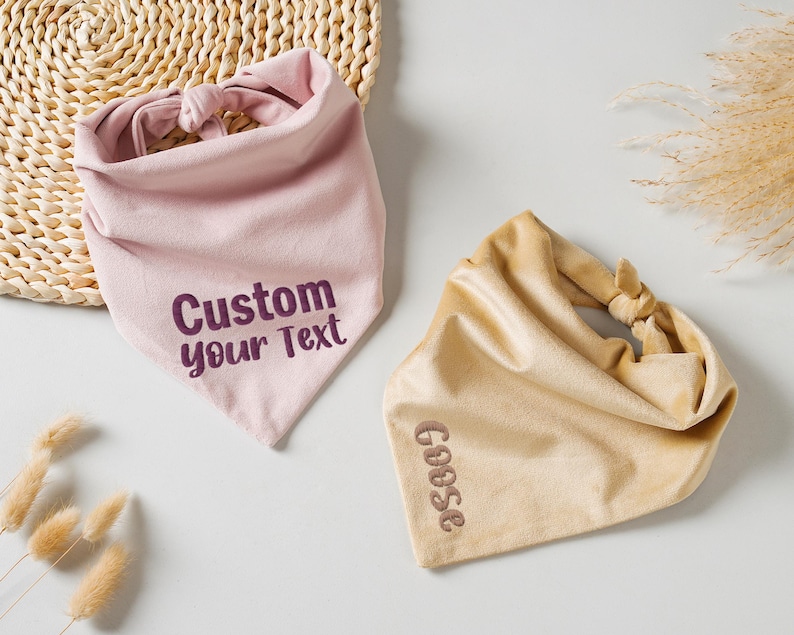 Puede incluir: Dos pa&ntilde;uelos para mascotas. Uno es rosa claro con el texto "Custom your Text" en morado oscuro. El otro es de color canela con el texto "Goose" en marr&oacute;n. Ambos pa&ntilde;uelos est&aacute;n anudados en la parte superior.