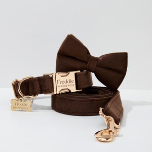 May include: A brown velvet dog collar and leash set with gold hardware. The collar has a personalized name tag that reads "Freddie (601) 812-8725". The leash has a gold hook.