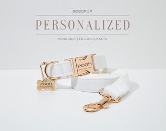 May include: White dog collar and leash set with gold hardware. The collar has a personalized name tag that reads "POOH" and a phone number. The leash has a matching gold hook. The tag also reads "POOH I'M CHIPPED".
