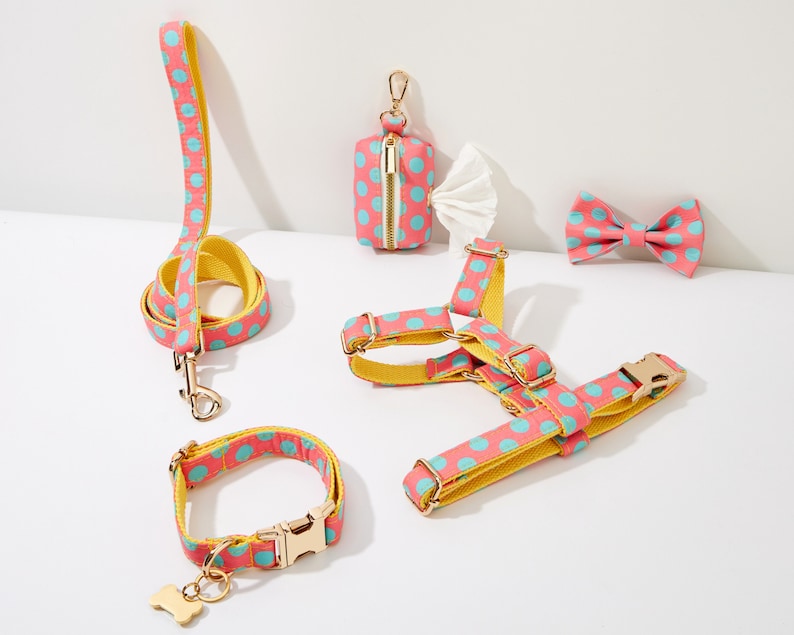 May include: A pink and blue polka dot dog harness, leash, collar, and bow tie. A matching pink and blue polka dot poop bag dispenser is also included.