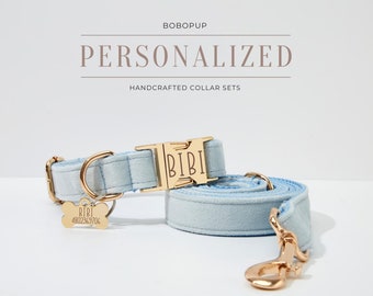 May include: A light blue dog collar and leash set with gold hardware. The collar has a personalized name tag that reads "Bibi". The leash has a gold hook.