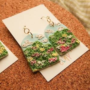 Brincos de paisagem com flores de pasto
