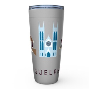 May include: A grey travel mug with a design of a church and other buildings in blue, brown, and maroon. The word "GUELPH" is printed in maroon on the lower part of the mug. The mug has a silver lid.