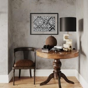 May include: A round wooden pedestal table with a dark brown finish, a dark wood chair with a brown seat, a black-framed abstract art print, a black lamp with a sculptural base, a brown textured sphere, and a white animal skull wall mount.