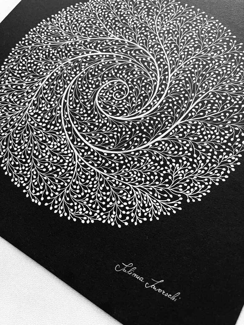 May include: A square black print featuring a white circular spiral design composed of intricate, branching, vine-like patterns with small rounded buds. The artist's signature, Juliana Iavorschi, is printed in white cursive in the bottom right corner.