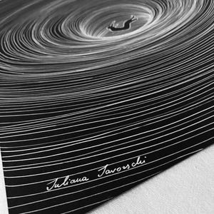 May include: A black and white art print featuring a central figure of a rabbit falling into a deep, swirling vortex of concentric white lines on a solid black background. The artist's signature, Juliana Favorschi, is written in white script at the bottom.