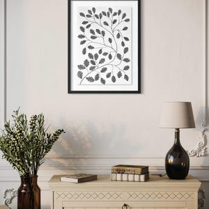 Pu&ograve; includere: Una stampa artistica da parete incorniciata che presenta un'illustrazione botanica in bianco e nero di rami di quercia con foglie dettagliate. L'opera &egrave; presentata in una sottile cornice nera con un passe-partout bianco, mostrando un motivo di fogliame.
