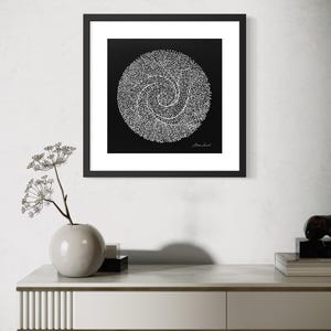 May include: A square framed wall art piece featuring a black background with a white circular design composed of intricate, swirling dotted lines. The artwork includes a signature in the bottom right corner and is enclosed in a thin black frame.