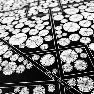 May include: A black and white ink drawing featuring a geometric pattern of interconnected squares and triangles filled with detailed illustrations of tree cross-sections. The artwork includes the signature Juliana Favorski in white script.