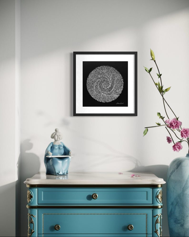 May include: A square black and white framed wall art print featuring a circular spiral pattern composed of tiny white dots on a solid black background, displayed in a black frame with a white mat border, hanging on a plain white wall.