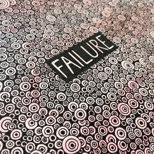 May include: Black and white illustration of a pattern of concentric circles with a pink gradient. The word "FAILURE" is written in white letters on a black rectangle.