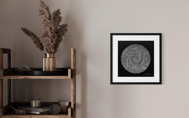 May include: A square framed wall art piece featuring a black background with a white circular spiral design composed of numerous small dots. The artwork is enclosed in a thin black frame with a white mat border, displaying a signature in the corner.