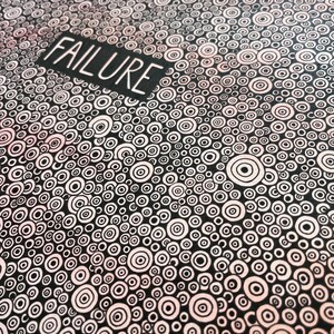 May include: Black and white abstract art print with a repeating pattern of concentric circles. The word "FAILURE" is written in white letters on a black rectangle at the top of the print.