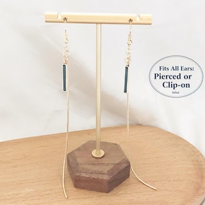 May include: A pair of long gold-tone chain earrings featuring a thin, dark rectangular bar accent. The earrings hang from a gold T-bar display stand. Text on the image reads: Fits All Ears: Pierced or Clip-on.