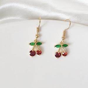 May include: Gold cherry earrings with red and green crystal accents.