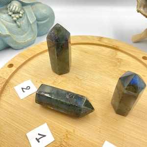 Puede incluir: Tres puntas de cristal de labradorita verde sobre una superficie de madera. Las puntas están etiquetadas con los números 1, 2 y 3.