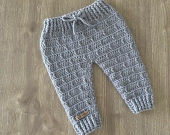 Puede incluir: Pantalones de ganchillo en color gris claro con cintura acanalada y cordón ajustable a juego. Los pantalones presentan un patrón de puntos texturizado en toda la prenda y puños acanalados en los tobillos. Incluye una etiqueta marrón.