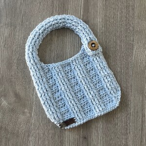 May include: A light blue crocheted baby bib with a wooden button.