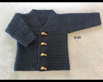 May include: A dark navy blue long-sleeve crochet cardigan featuring a V-neckline and four light brown buttons shaped like construction vehicles. The garment has a textured waffle stitch pattern and includes the printed text 0-3Y.