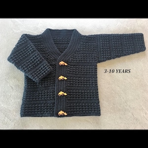 May include: A dark navy blue long-sleeve cardigan with a textured waffle stitch pattern, a V-neckline, and four light brown buttons shaped like construction vehicles. The text 3-10 YEARS is printed on the right side of the garment.
