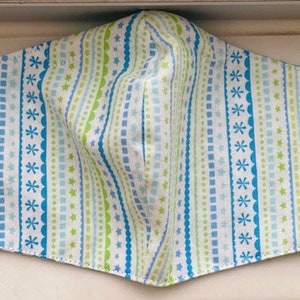 May include: A blue and green striped face mask with a white background. The fabric has a repeating pattern of stars, squares, and wavy lines.