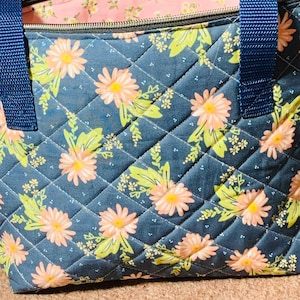 Bolsa multiusos acolchada con estampado floral azul marino y melocotón de 12”x8”x4” con bolsillo lateral para teléfono y cierre de cremallera