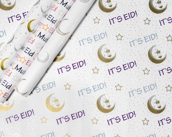 Könnte beinhalten: Weißes Geschenkpapier mit einem sich wiederholenden Muster aus goldenen Halbmonden, Sternen und dem Text "It's Eid!" in Lila. Das Papier ist aufgerollt und die Enden sind sichtbar.