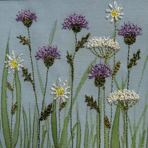 Un joli groupe de fleurs sauvages composé de chardons, de marguerites et de cow-boys parmi les herbes et les feuilles.