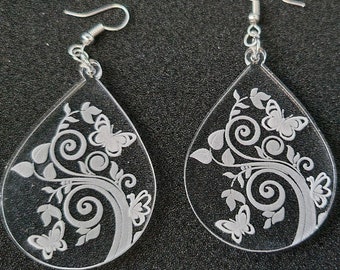 May include: A pair of teardrop-shaped earrings with a silver hook and a white floral design featuring butterflies. The earrings are made of clear acrylic.