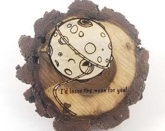 May include: A wooden slice with a burned design of a lasso around the moon. The text "I'd lasso the moon for you!" is burned into the wood.