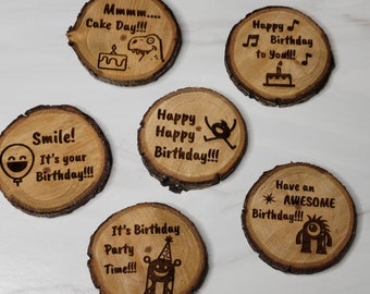 May include: Six wooden round slices with different birthday messages and illustrations. The messages include "Happy Happy Birthday", "It's Birthday Party Time", "Smile! It's your Birthday", "Have an Awesome Birthday", "Happy Birthday to You", and "Mmmm... Cake Day!"